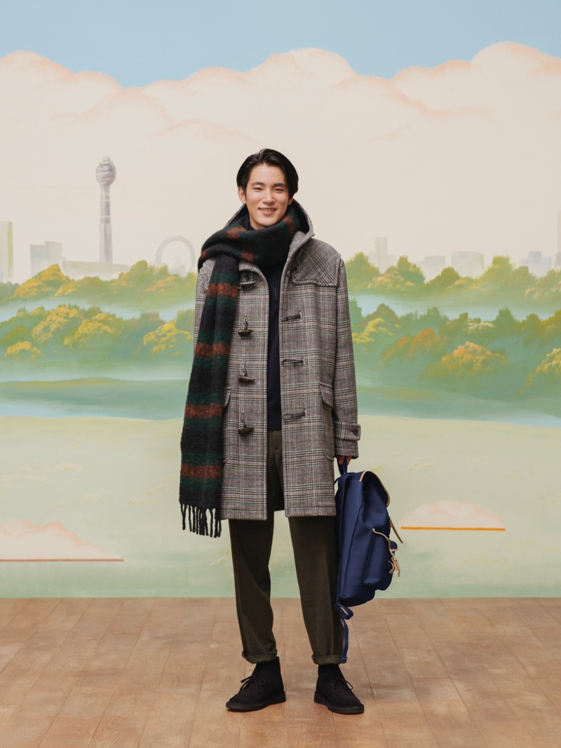 All smiles, model Hikaru Takakamo wears a checked duffle coat, pleated trousers, and a striped scarf from the UNIQLO x JW Anderson fall-winter 2020 collection.