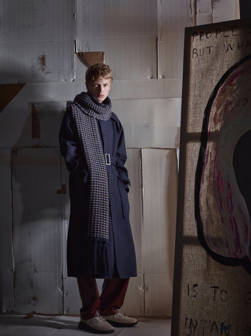 Front and center, Jonas Glöer sports a navy belted coat with a long chunky scarf and billowing trousers for Zara's fall-winter 2020 men's campaign.