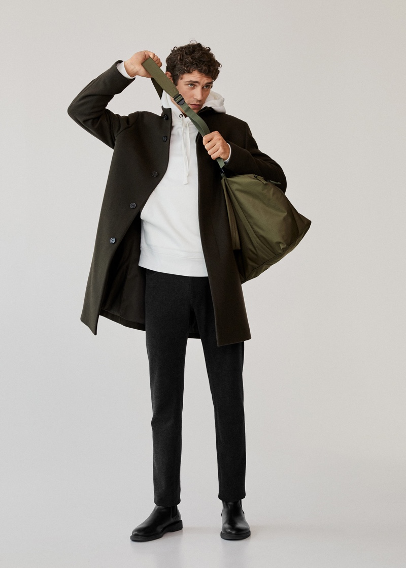 French model Arthur Gosse dons Mango Man's tailored wool-blend overcoat with a white hoodie and pants.