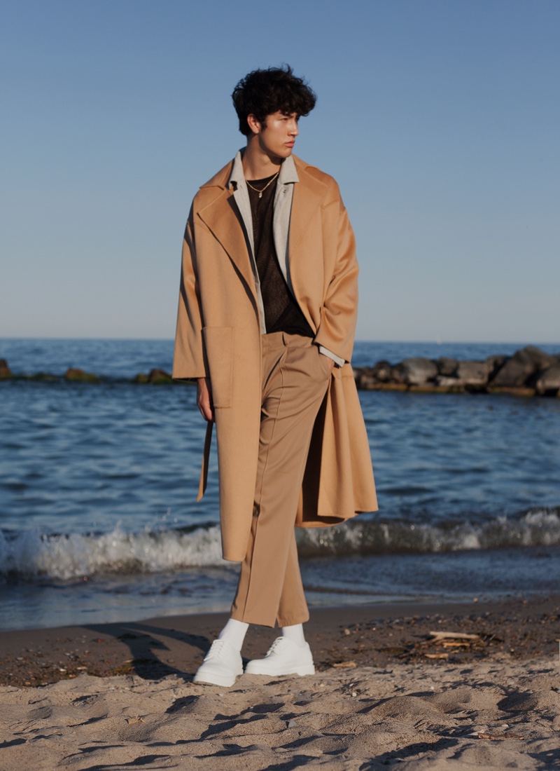 Brandon wears shirt ASOS Design, trousers Saint Laurent, jacket Zegna, coat Nanushka, socks Calvin Klein, and shoes Jacquemus. 