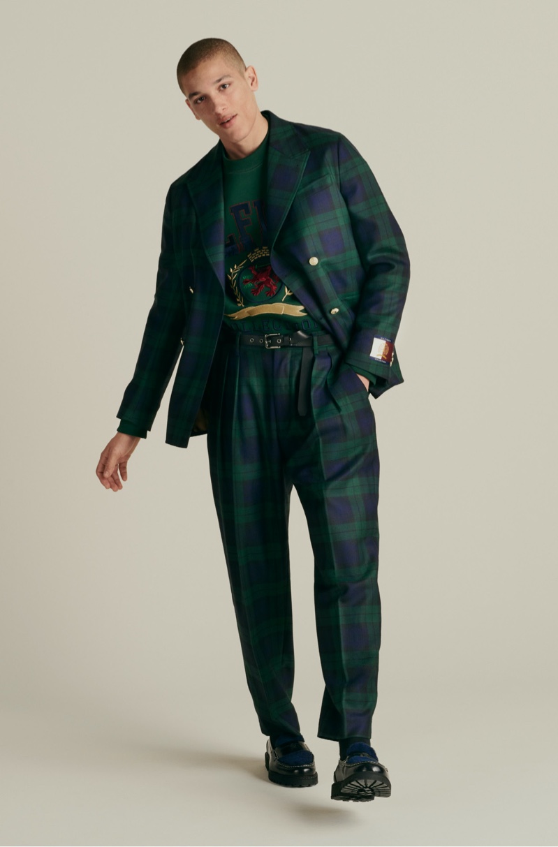 Going sartorial, Marco Pickett wears a Hilfiger Collection boxy check blazer and tapered pants with a bonded fringe logo sweatshirt, and skinny rock belt.