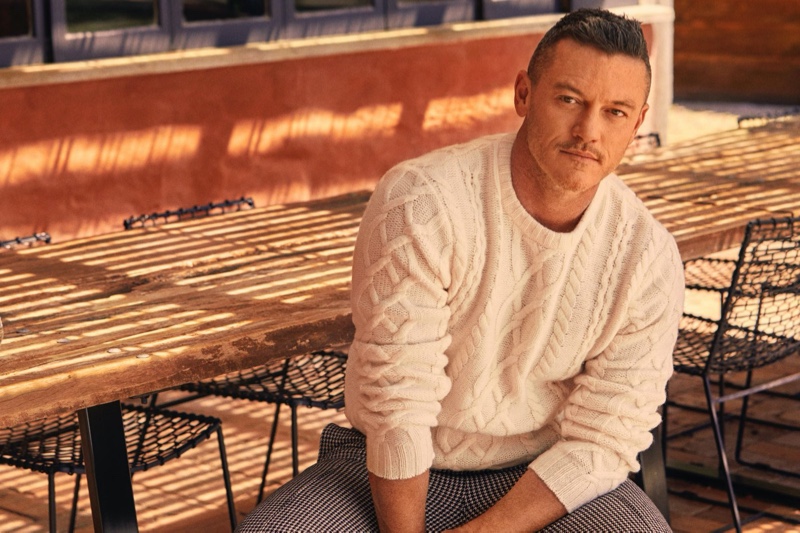 Actor Luke Evans sports a Todd Snyder cable fisherman's sweater in off white with cream and black houndstooth wool pleated pants.