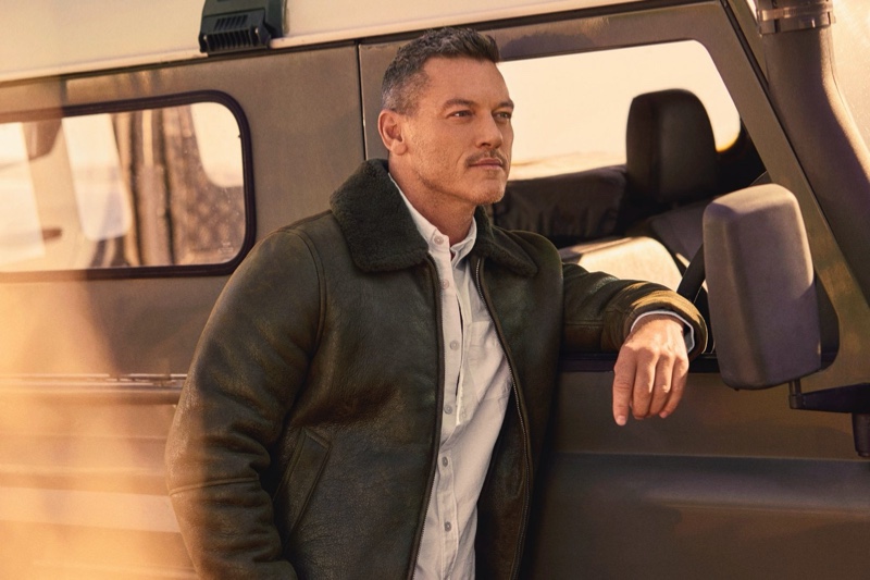 Sporting Todd Snyder's shearling aviator jacket in olive, Luke Evans also wears the brand's solid oxford shirt in white.