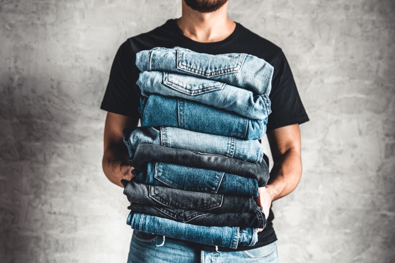 Man Holding Stack Folded Jeans Denim