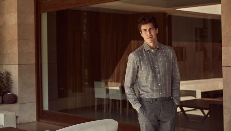 Model Oriol Elcacho dons a grey check shirt with pleated trousers from Pedro del Hierro.