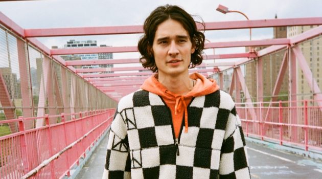 Saturdays New York City Launches Capsule for the Daily Commute Sebastião Hungerbühler sports Saturdays New York City's checked polar fleece half-zip with an orange hoodie and the brand's Dean trousers.