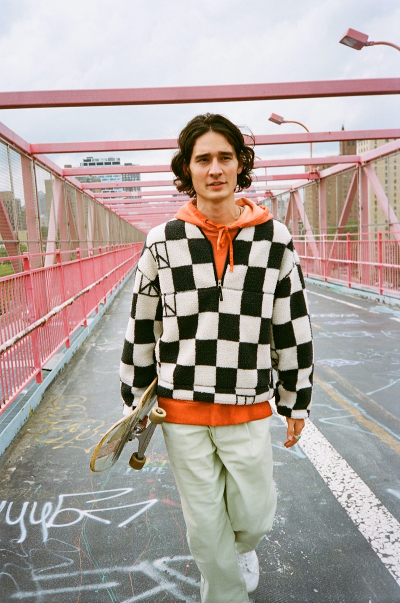 Sebastião Hungerbühler sports Saturdays New York City's checked polar fleece half-zip with an orange hoodie and the brand's Dean trousers.