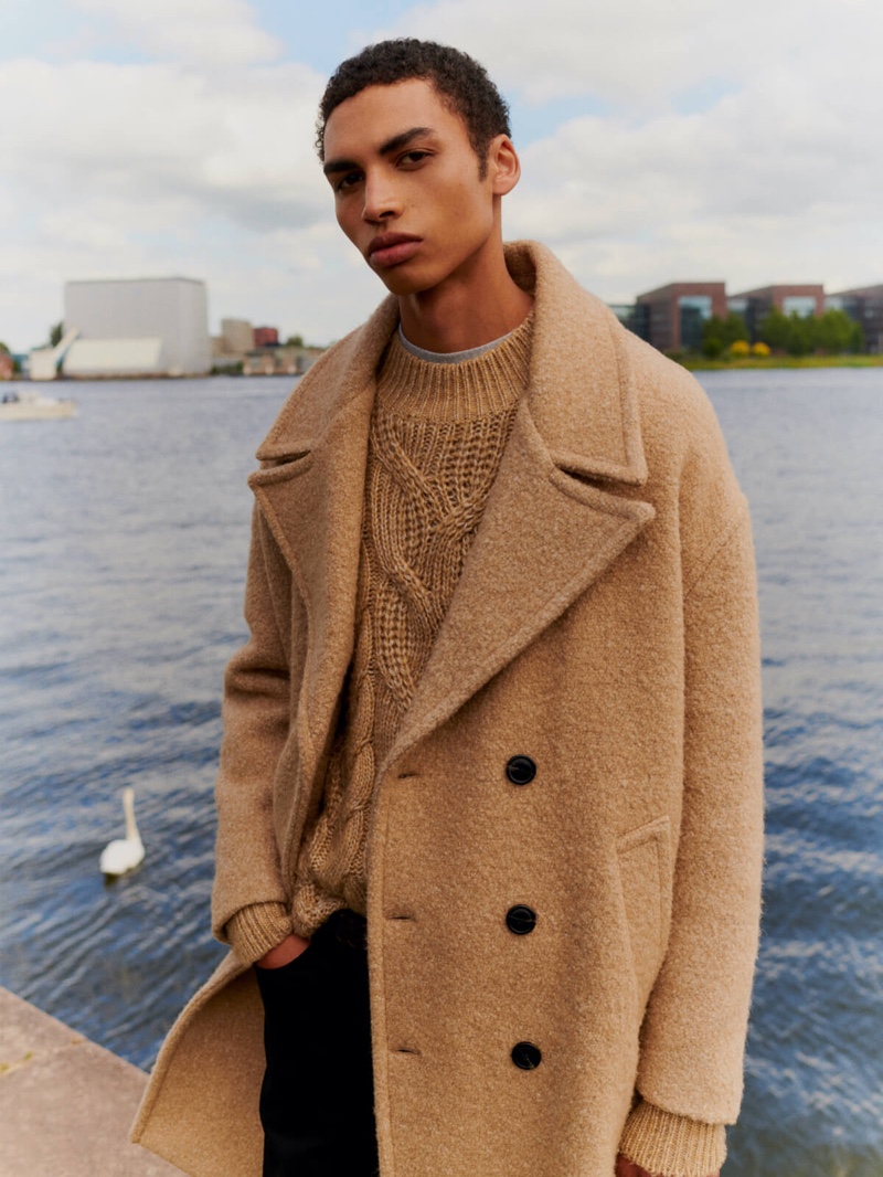 Sol Goss dons a chic winter coat with a cable-knit sweater from Scotch & Soda.