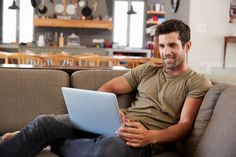 Smiling Man Couch Laptop Green Shirt