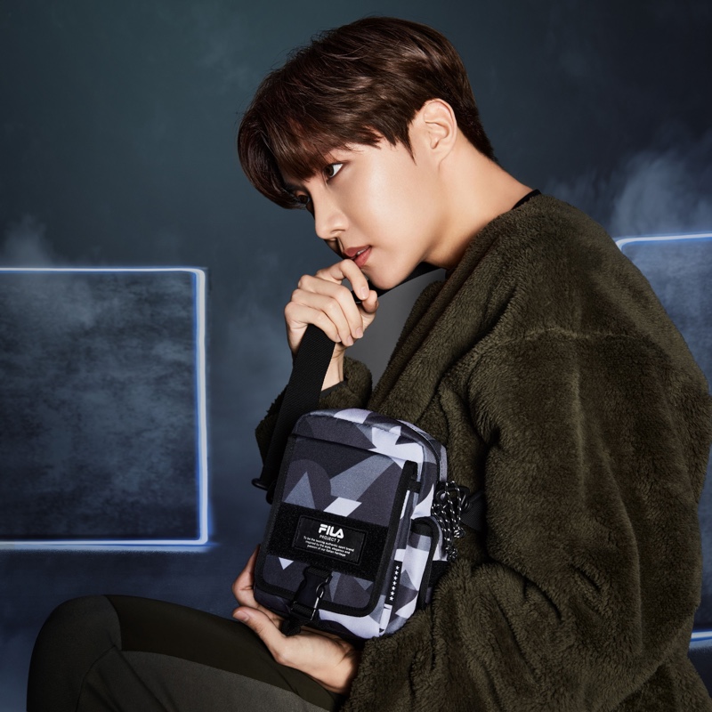 Taking hold of FILA's Project 7 small nylon bag in military khaki, J-Hope wears a Boa fleece sweatshirt for the collection campaign.