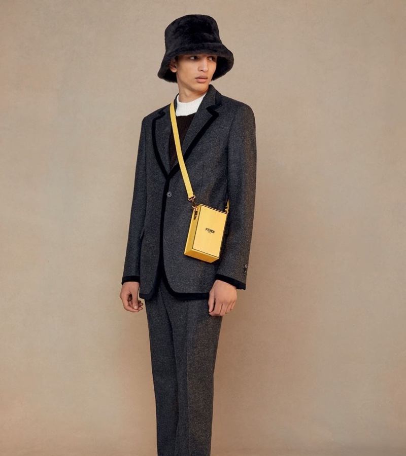 A chic vision, Jethro Sapon models a gray suit with black piping, finished with a bucket hat and yellow leather bag.