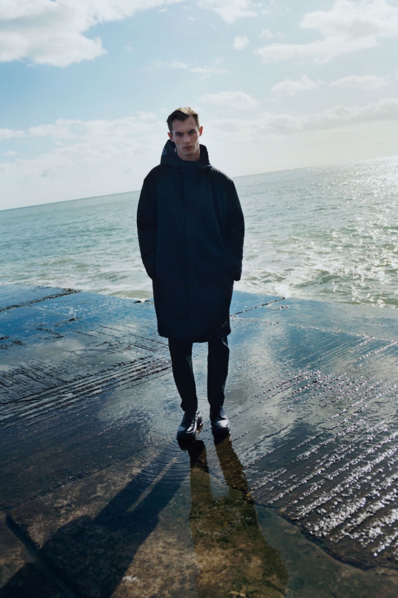 British model Kit Butler sports a COS recycled polyamide down-lined waterproof coat with skinny stretch-cotton trousers, and chunky leather Chelsea boots.