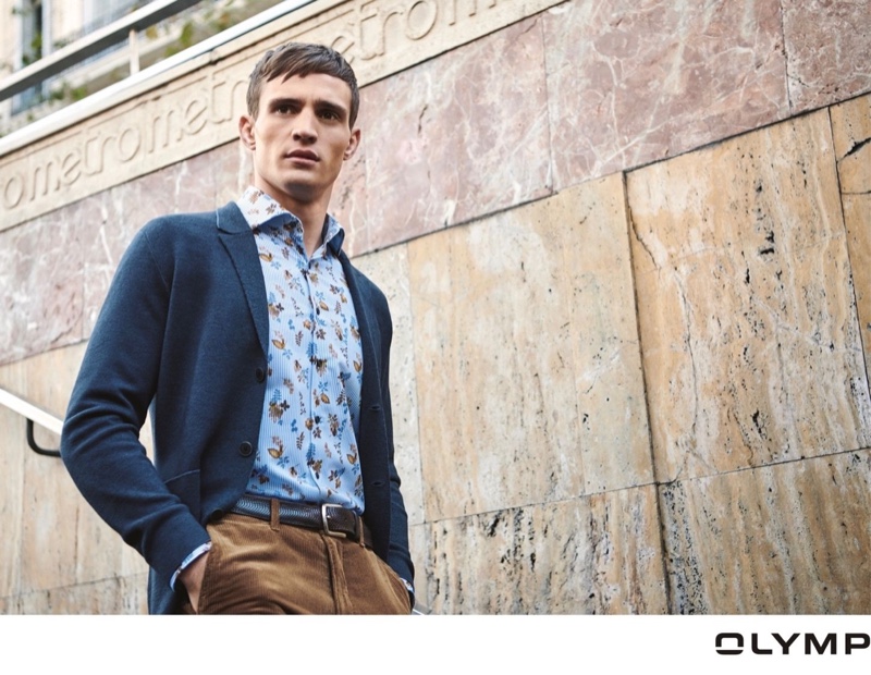 Donning a knit blazer with a floral print shirt and corduroy pants, Julian Schneyder sports a look from OLYMP.