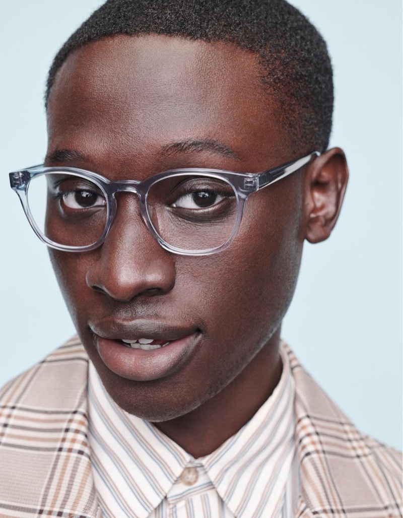 Front and center, Baba Diop models Warby Parker's Felix glasses with a low bridge fit in pacific crystal.