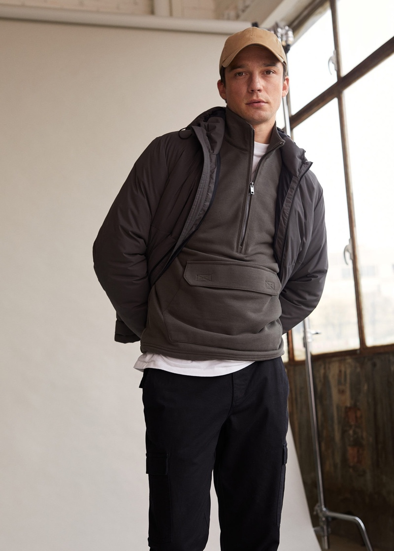 Layering for a cool day, Alexis Petit wears a half-zip pullover with a jacket and cargo pants from Mango Man.