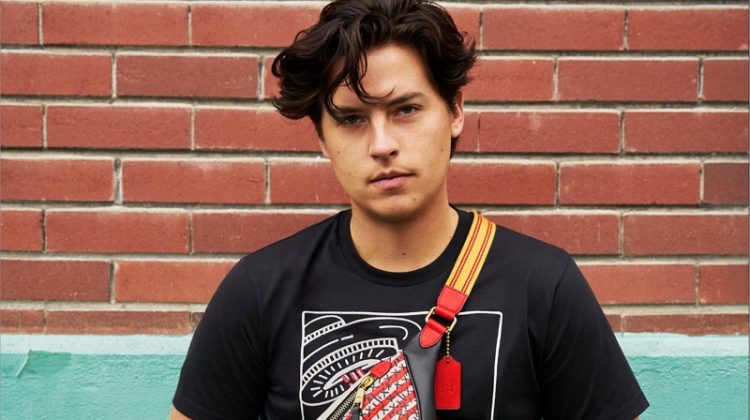 Cole Sprouse rocks a Coach Disney Mickey Mouse x Keith Haring Rivington belt bag with a t-shirt.