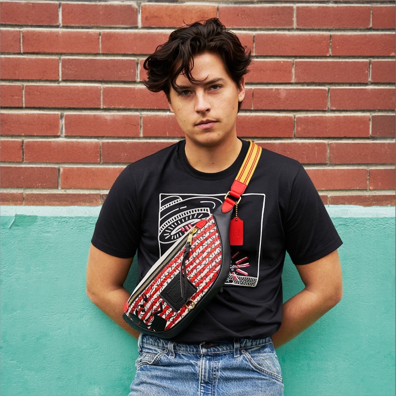 Cole Sprouse rocks a Coach Disney Mickey Mouse x Keith Haring Rivington belt bag with a t-shirt.