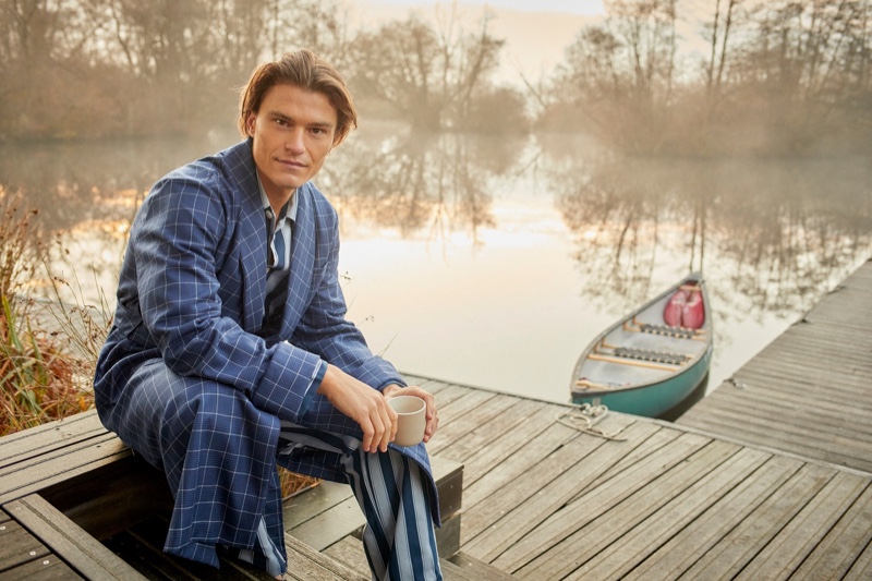 Connecting with Derek Rose for the season, Oliver Cheshire dons a men's navy check tasseled belt robe in pure wool with a striped pajama set.