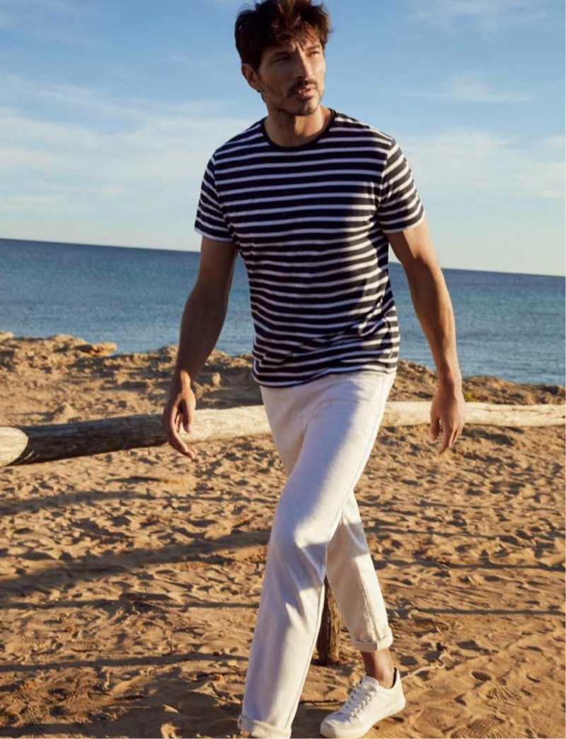 Hitting the beach, Andres Velencoso rocks a striped tee with white jeans from Esprit's spring-summer 2021 men's collection.