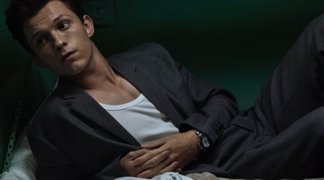 Lounging, Tom Holland dons a Prada suit, Hanes tank, and Rolex watch for Esquire.