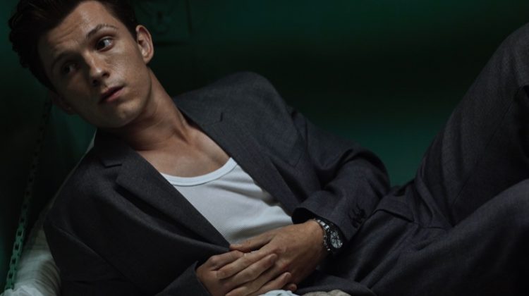 Lounging, Tom Holland dons a Prada suit, Hanes tank, and Rolex watch for Esquire.