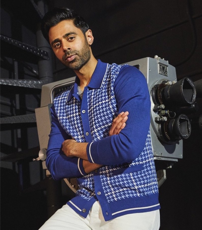 Front and center, Hasan Minhaj dons a Todd Snyder long sleeve houndstooth plaid polo and white slim fit Japanese selvedge stretch jeans.