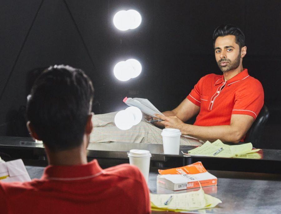 Reporting for work, Hasan Minhaj wears a Todd Snyder Italian cotton. silk tipped ribbed polo sweater with Italian tattersall Sutton dress trousers.