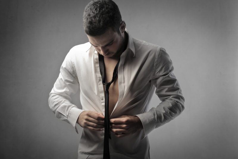 Man Putting on Shirt and Tie