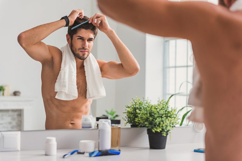 Mens Grooming Male Model Shirtless Combing Hair in Mirror