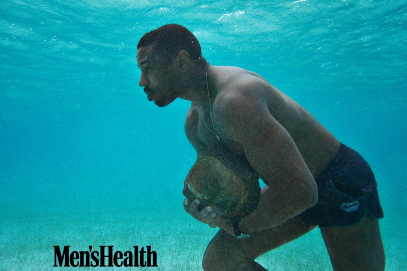 Michael B. Jordan trains underwater with Men's Health. The actor wears a watch and swim shorts by Coach.