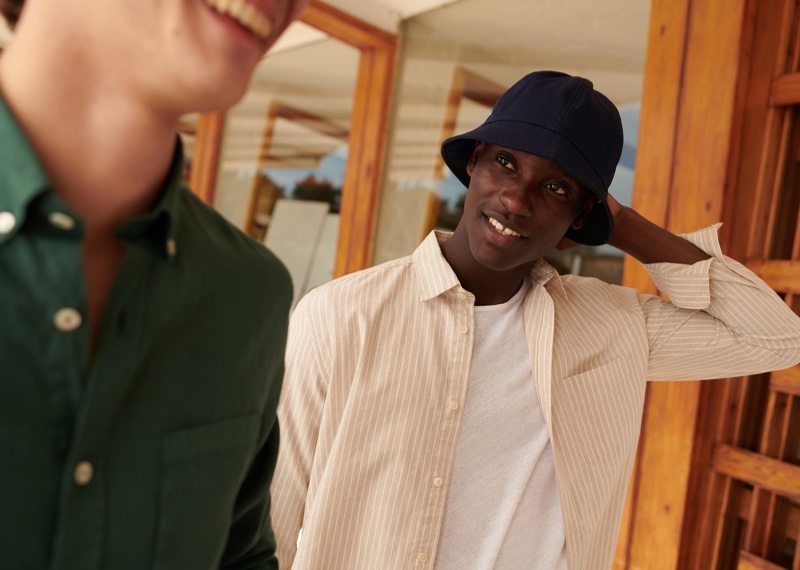 All smiles, Charles Oduro wears a bucket hat and striped shirt from Octobre's Motel Paradise collection.