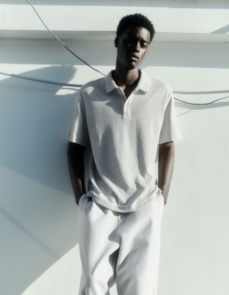 Front and center, Babacar N'doye wears a COS terry polo shirt with elasticated tapered leg trousers.