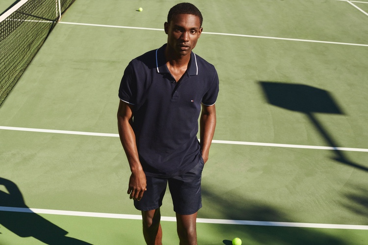 Sporting a navy polo, Victor Ndigwe models a tennis look from Tommy Hilfiger.