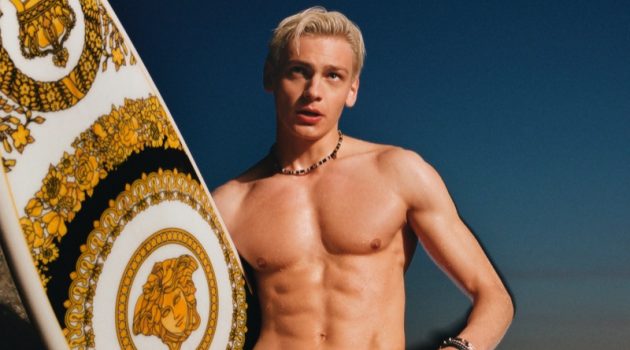 Taking hold of a Versace surfboard and wearing red swim shorts, Lucas Barski fronts the Versace La Vacanza campaign.