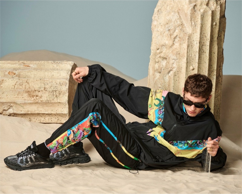 Rocking a jogging suit, sunglasses, and sneakers, Valentin Humbroich appears in Versace's spring-summer 2021 men's accessories campaign.