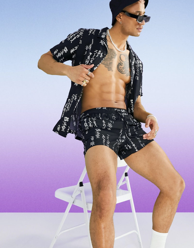 Making a printed statement, Nathan Hopkinson models an ASOS DESIGN shirt and swim shorts set in a monochrome japanese print.