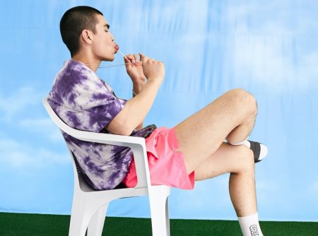 Showcasing the latest trends, Del Winder wears a tie-dye t-shirt with ASOS's COLLUSION short swim shorts in neon pink.