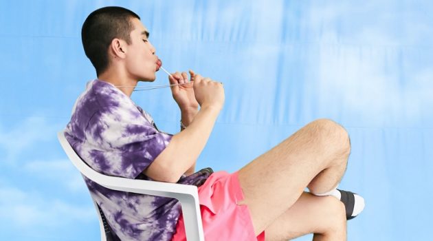 ASOS Makes a Splash with New Swimwear Arrivals Showcasing the latest trends, Del Winder wears a tie-dye t-shirt with ASOS's COLLUSION short swim shorts in neon pink.