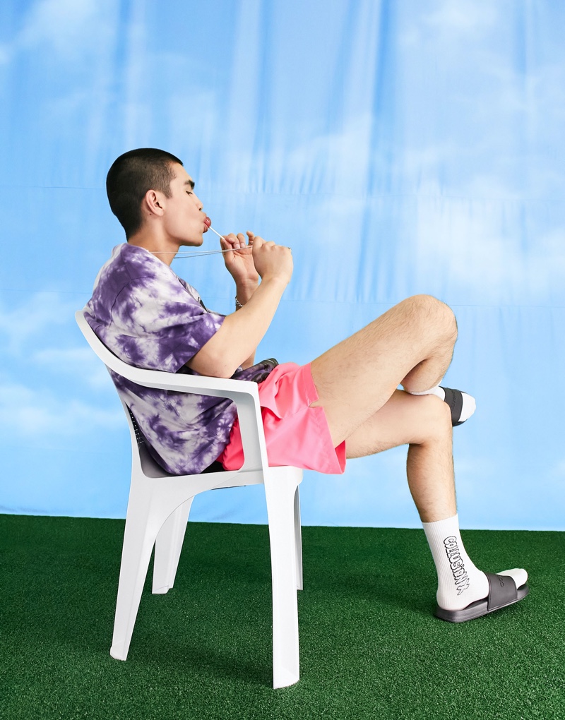 Showcasing the latest trends, Del Winder wears a tie-dye t-shirt with ASOS's COLLUSION short swim shorts in neon pink.