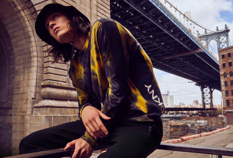 Peter Meyer models a tie-dye sweatshirt with a bucket hat and joggers from DKNY's fall-winter 2021 men's collection.