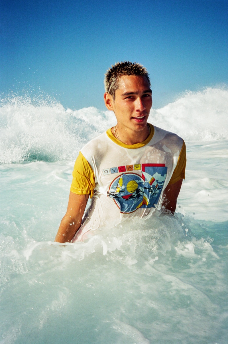 Partially submerged in water, Evan Mock sports a tourist blocked short-sleeve tee from his RVCA collaboration. Photo Credit: Julian Klincewicz