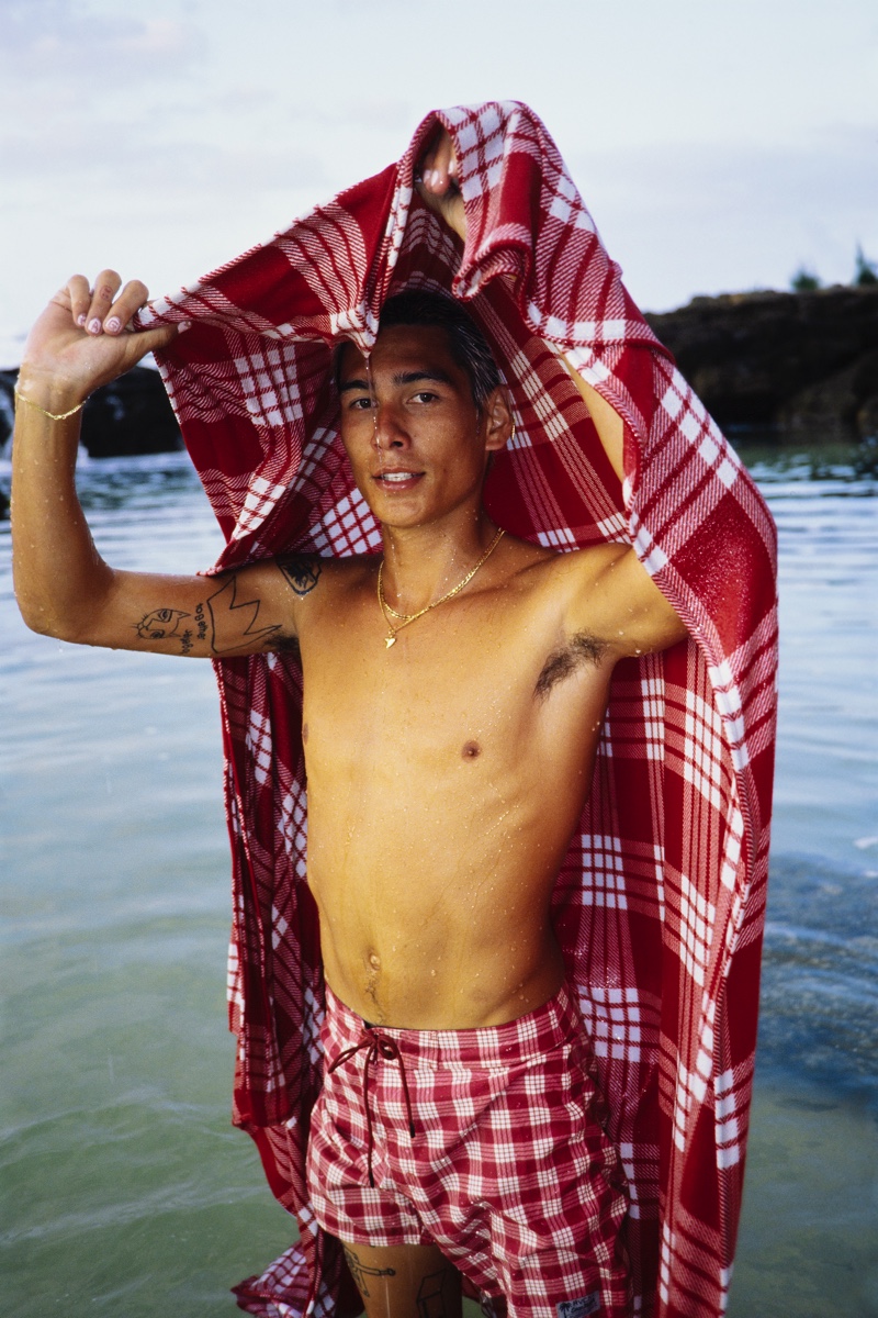 Taking to the beach, Evan Mock wears his RVCA Palaka plaid board shorts and covers up in a matching blanket.