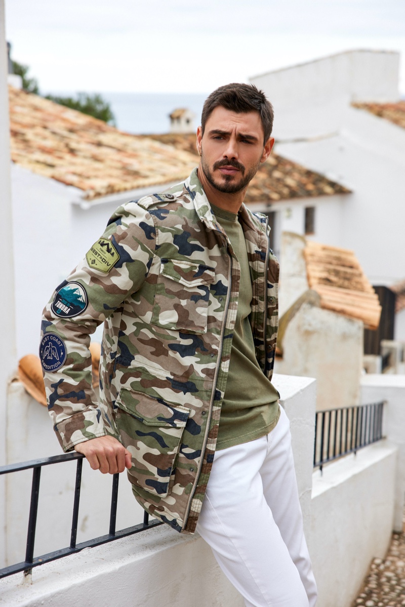 Rocking a camouflage jacket with white jeans, Francesco Monte fronts GUESS' summer 2021 men's campaign.