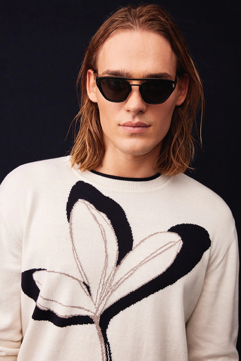 Ready for his close-up, Ton Heukels models a knit sweater and modern shades from Giorgio Armani's spring-summer 2022 collection.