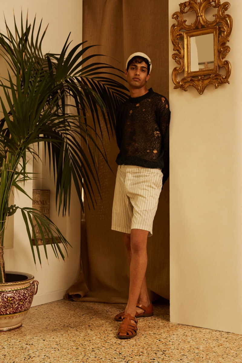 Modeling a spring-summer 2022 look from Luca Larenza, Matteo Tagliabue is pictured in a deconstructed sweater and striped shorts.