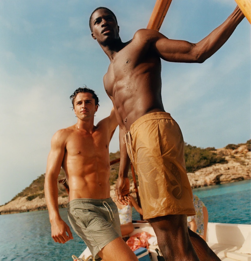Models Alberto Perazzolo and Mukasa Kakonge sport swim shorts from Mango Man's summer 2021 collection.
