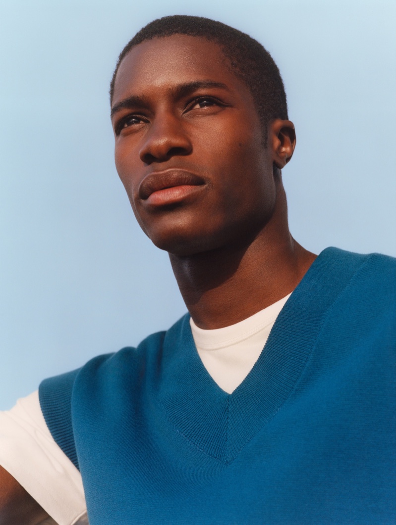 Front and center, Mukasa Kakonge dons a blue sweater vest from Mango Man's summer 2021 collection.