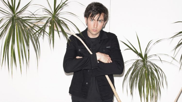 Standing tall at 6'7", Nicholas Braun wears an all-black look for a British GQ photoshoot. He sports a t-shirt, jacket, and jeans from Dolce & Gabbana with Grenson boots.