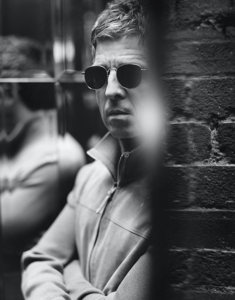 Appearing in a black and white image for Mr Porter, Noel Gallagher wears a Tom Ford suede and merino wool blouson jacket with Saint Laurent D-Frame silver-tone sunglasses.