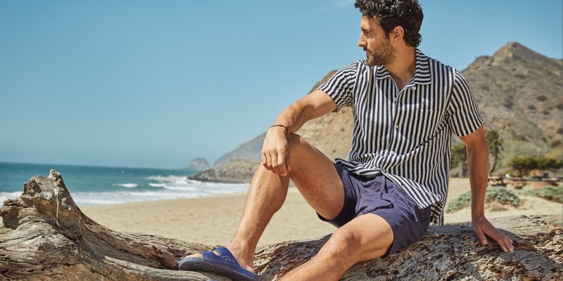 Noah Mills relaxes in a Todd Snyder vertical stripe terry button-down polo and 7" weekend shorts with Freedom Moses sandals.